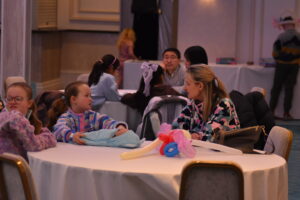  A small group sitting around round tables, chatting and working on crafts in a relaxed setting"