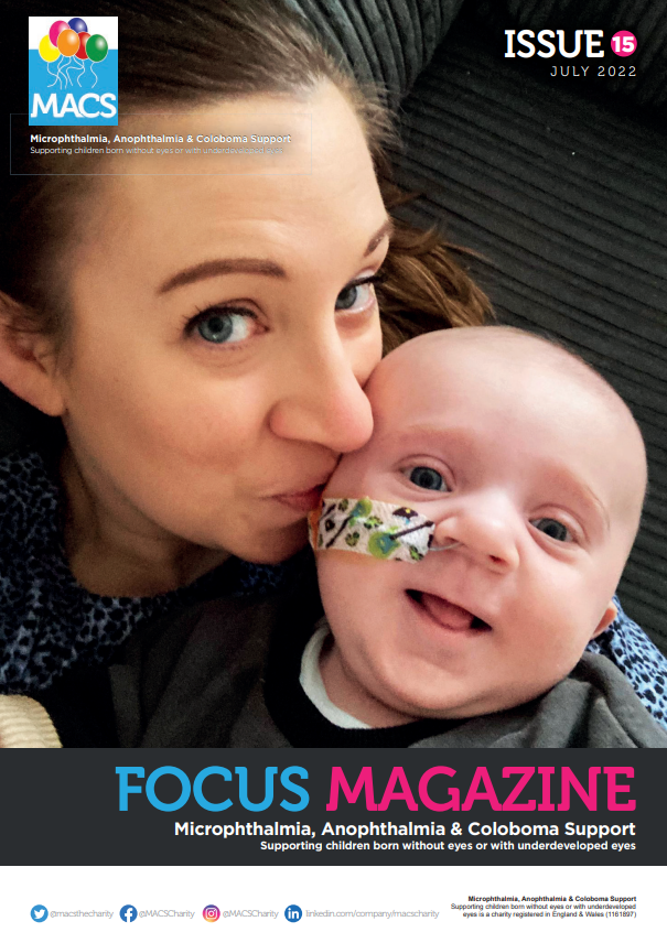 The cover shows two individuals leaning closely together indoors. Both are positioned in front of a dark‑coloured, textured background. One individual is holding a soft toy shaped like an owl, which is prominently visible in the foreground. The top of the cover includes the MACS logo and “ISSUE 15.” At the bottom is the familiar FOCUS MAGAZINE branding with the MACS support subtitle.