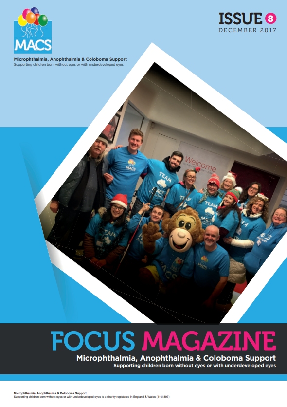 The cover features a lively group of people indoors, wearing matching bright blue shirts, standing close together and smiling toward the camera. One person is dressed in a friendly mascot-style character costume with a large head resembling an animal or cartoon figure. The image is framed at an angle like a pinned photograph. The top section is light blue with the MACS logo on the left and “ISSUE 8 Spring 2016” on the right. The bottom banner again displays “FOCUS MAGAZINE” and the subtitle “Microphthalmia, Anophthalmia & Coloboma Support.”