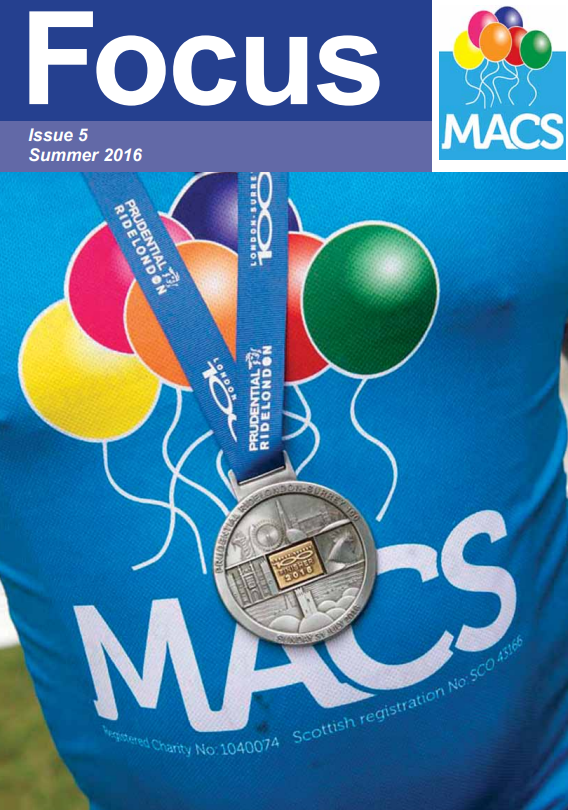 The cover displays a close-up image of a bright blue MACS T‑shirt with the organisation’s balloon graphic printed on it. Resting on the shirt are two medals: one attached to a blue ribbon, and the other hanging beside a cluster of balloons printed on the fabric. The focus is on the medals and the MACS branding. The top banner is dark blue with the title “Focus”, the text “Issue 5 Summer 2015”, and the MACS logo.