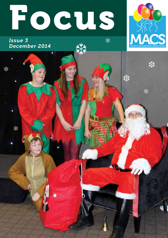 The cover features a festive holiday scene with several people in Christmas costumes. Some are wearing bright red and green outfits, resembling elves, while another individual is dressed in a classic red and white Santa-style outfit and seated next to a large red sack. The background includes seasonal decorations such as stars. The top banner is dark green with the title “Focus”, the text “Issue 3 December 2014”, and the MACS logo.
